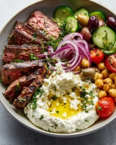 Mediterranean steak bowl with marinated steak, colorful veggies, and vibrant sauce